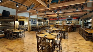 A spacious restaurant with wooden tables and chairs, high ceilings with exposed beams, and a bar area. - Great Wolf Lodge Wisconsin Dells (Baraboo)