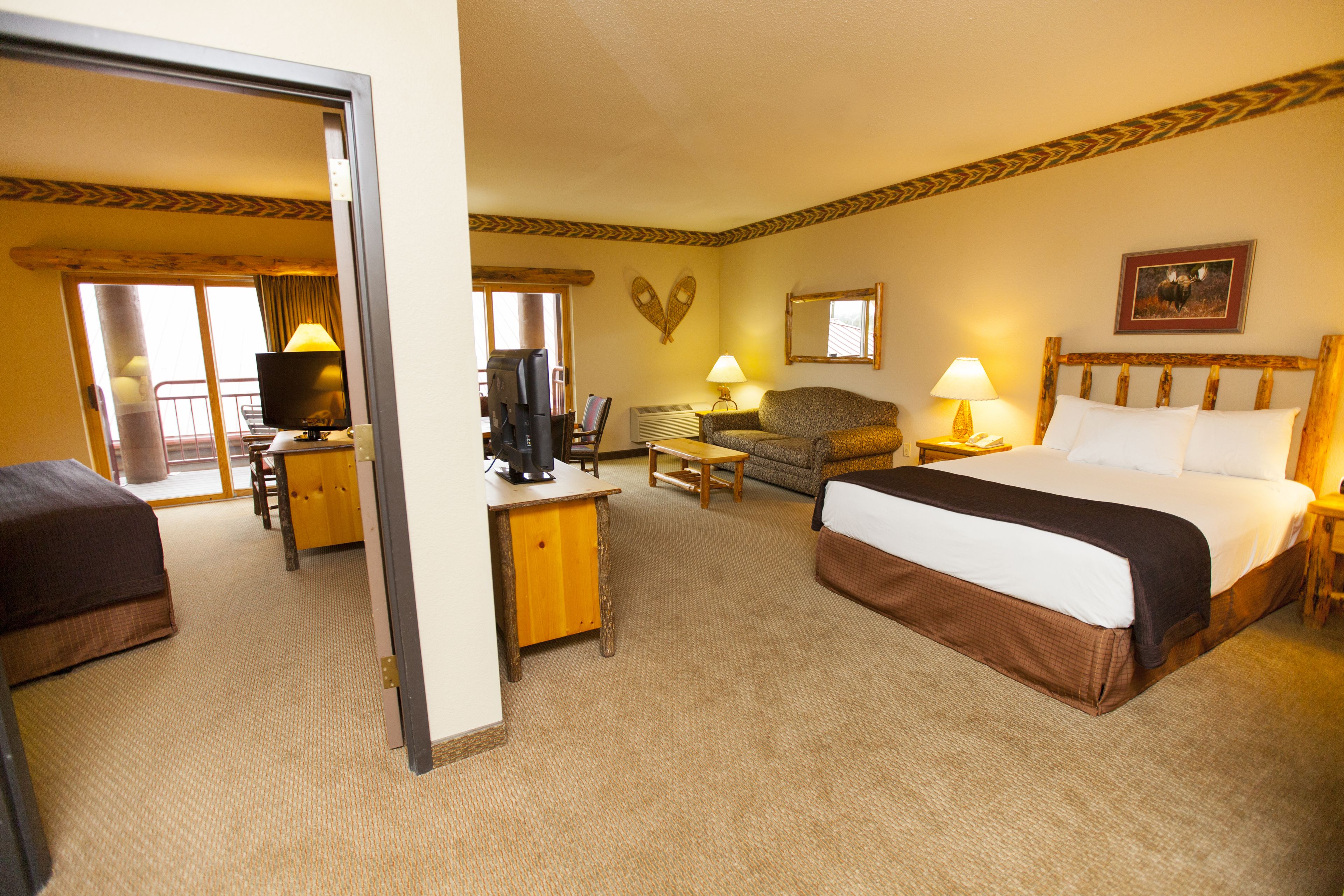 Quarto de hotel com cama, escrivaninha, cadeira, sofá e televisão.