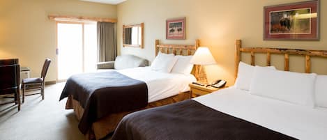 Ein Hotelzimmer mit zwei Betten, einem Schreibtisch, einem Stuhl und einem fensterbepflanzten Fenster.
