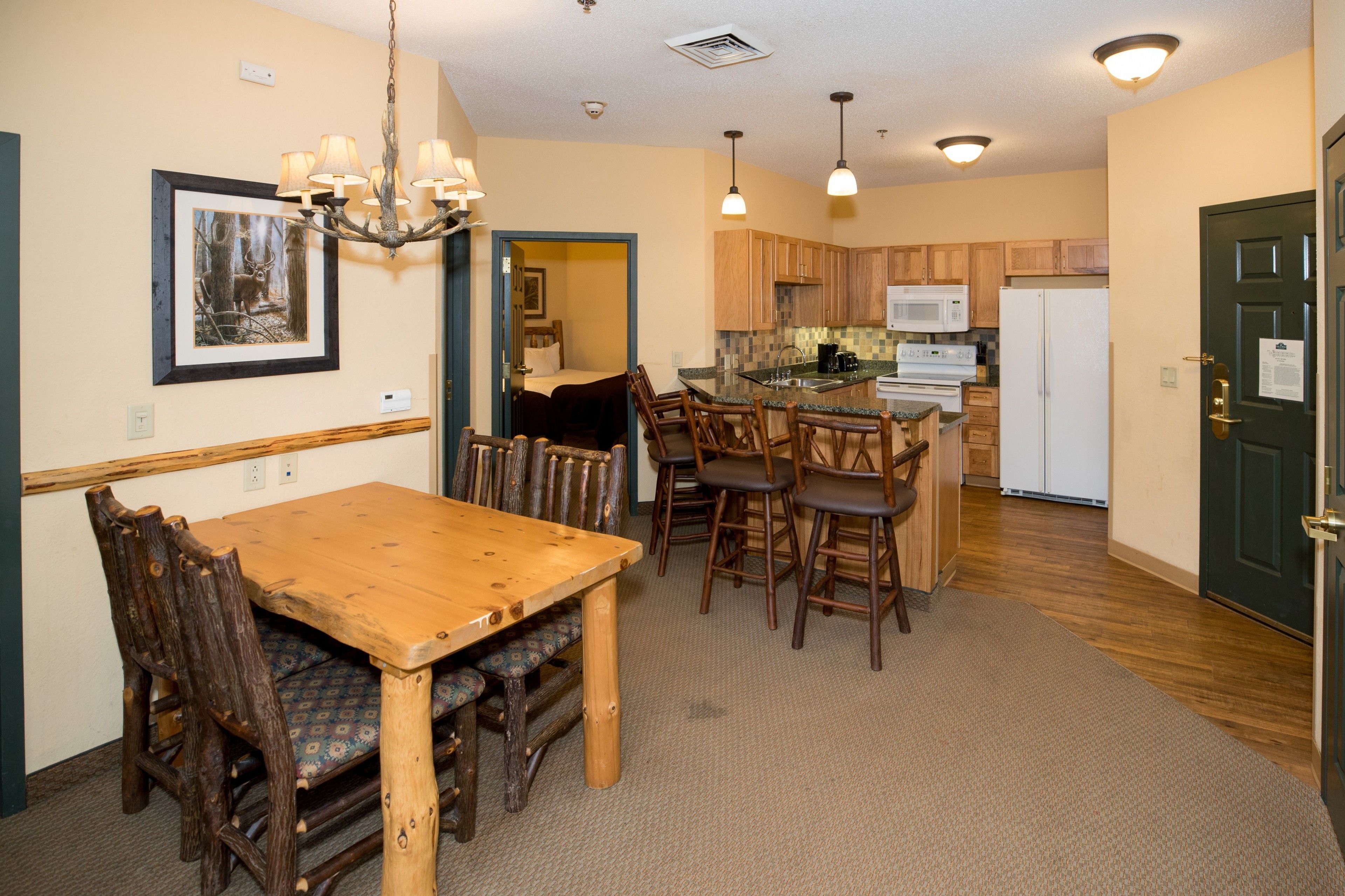 A cozy kitchen with wooden cabinets, a dining table with chairs, and a chandelier.
