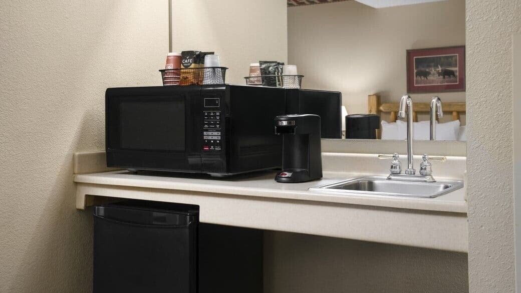 A kitchenette with a microwave, coffee maker, and a sink.