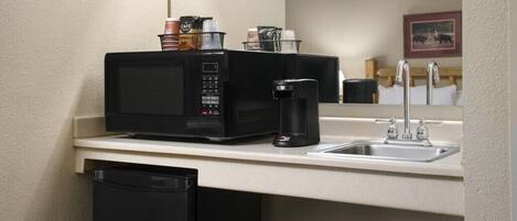 A kitchenette with a microwave, coffee maker, and a sink.