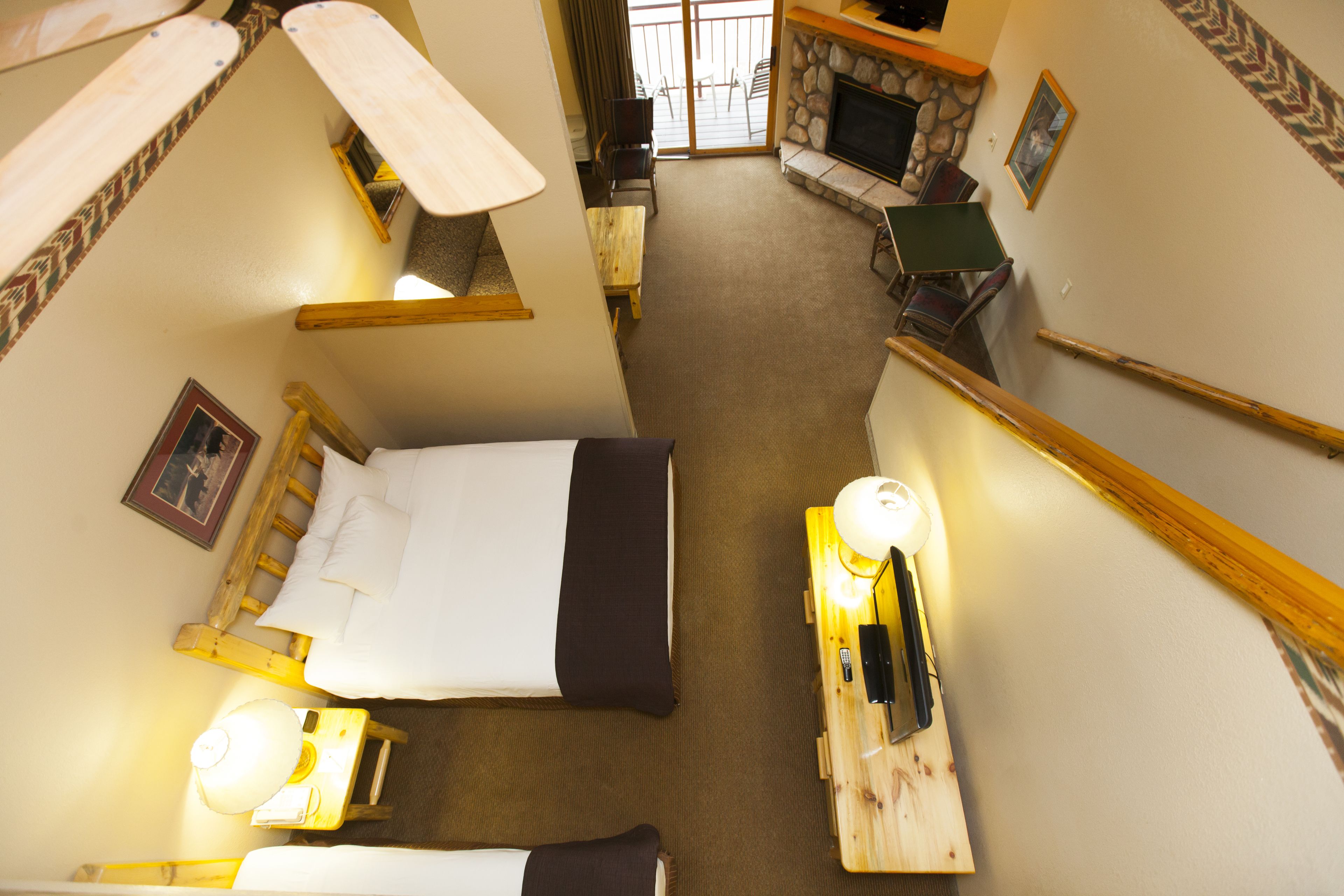 Una habitación de hotel con cama, escritorio con lámpara, televisión y chimenea.