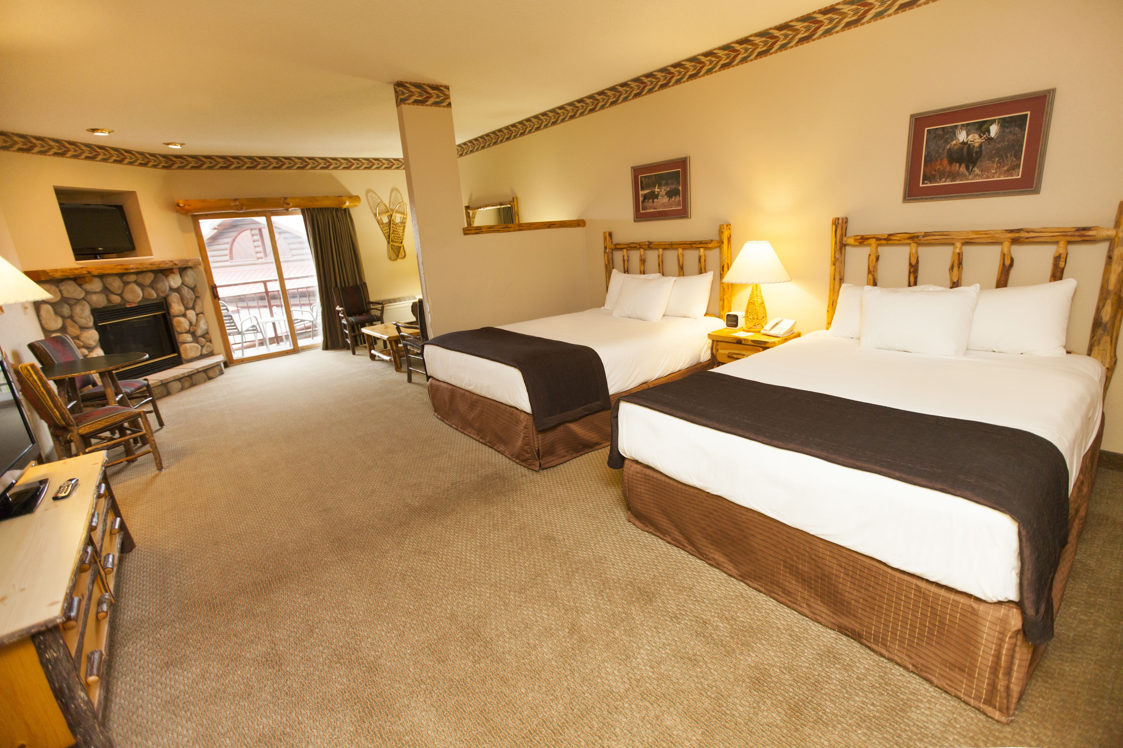 A hotel room with two beds, a fireplace, a TV, and a balcony with a view.