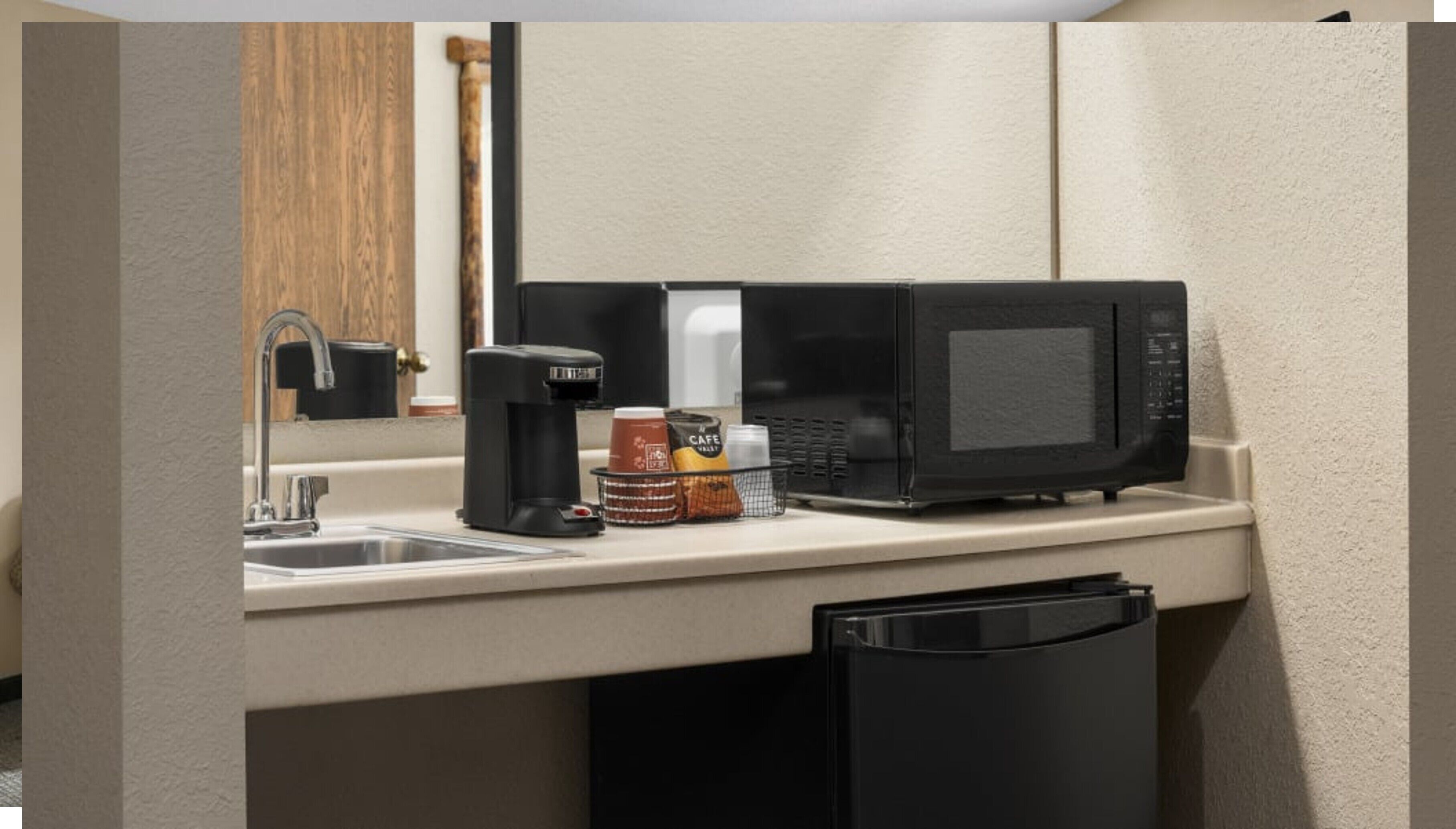A kitchenette with a coffee maker, microwave, and coffee cups.