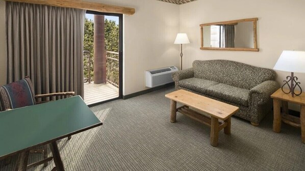 A room with a sofa, a small table, a chair, a lamp, and a large window with curtains.
