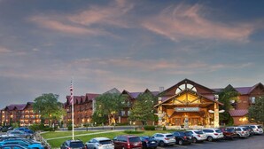 A lodge with a prominent entrance, multiple parking spaces, and a flagpole. - Great Wolf Lodge Wisconsin Dells (Baraboo)