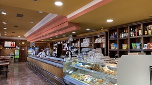 Eine Bäckereitheke mit verschiedenen Backwaren sowie einer Auswahl an Snacks und Getränken.