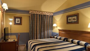Ein Hotelzimmer mit zwei Betten, einem Schreibtisch, einem Stuhl, einer Lampe und einem Vorhang.
