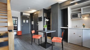 A modern kitchen with a microwave, a sink, and a small countertop. There is a dining table with two chairs and a potted plant on it. - The Originals Boutique, Hôtel d'Alsace, Strasbourg Sud (Illkirch-Graffenstaden)
