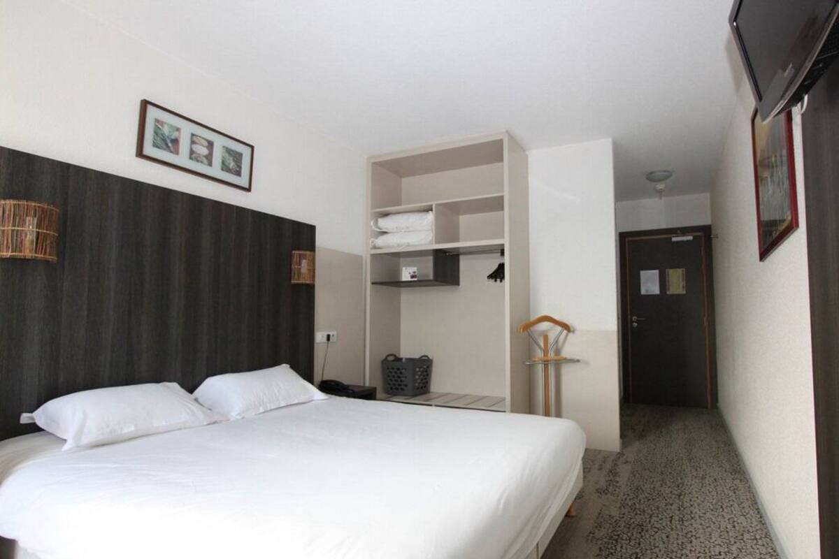 Une chambre d’hôtel avec un lit, une armoire, un bureau et une chaise.