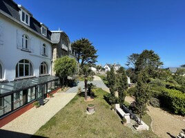 A courtyard with a glass conservatory, stone buildings, and a well-maintained garden with pathways and seating areas.