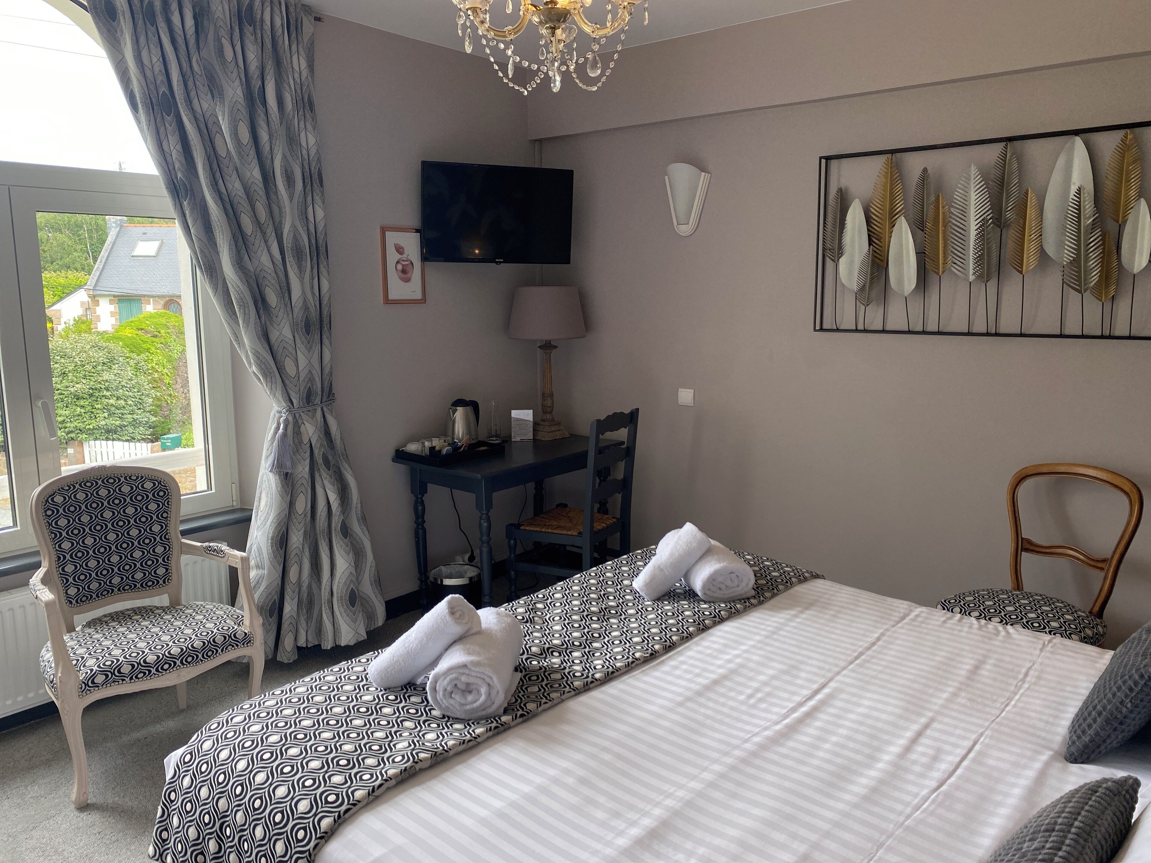 Een hotelkamer met een bed, een bureau, een stoel, een televisie en een raam met gordijnen.