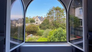 A window with a clear view of a residential area, including houses and greenery. - L'Escale Hôtel Bellevue (Tregastel)