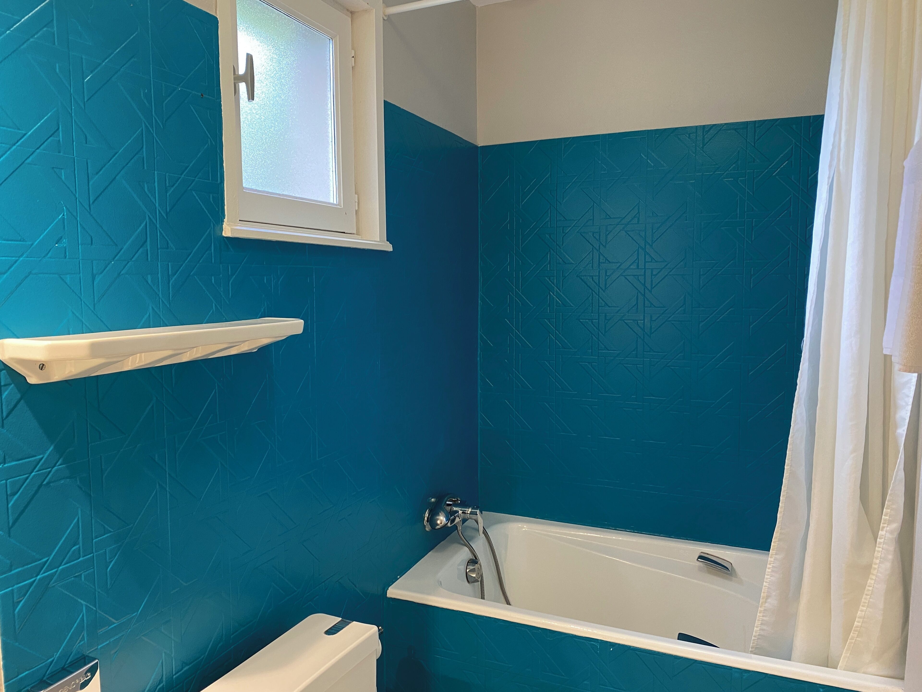 A bathroom with a bathtub, a toilet, and a window.