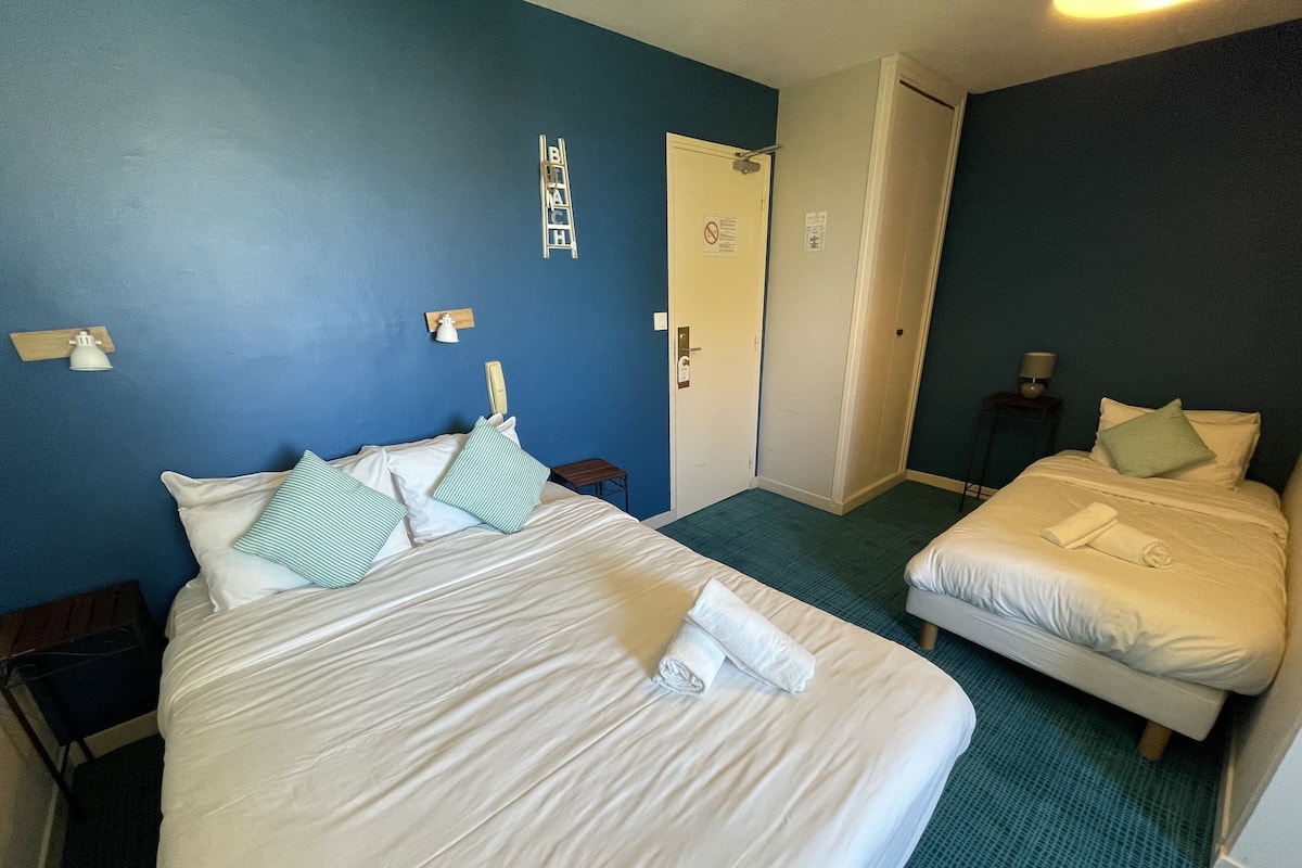 A hotel room with a large bed, a smaller bed, and a door.
