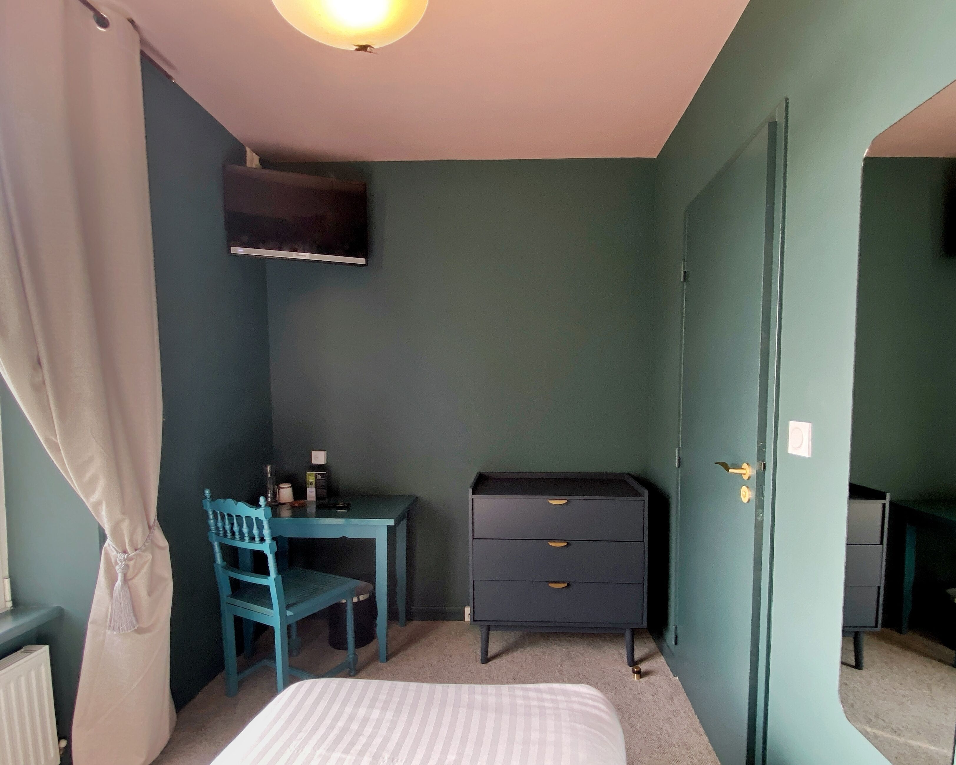 Una habitación con cama, escritorio, silla, cómoda y puerta.