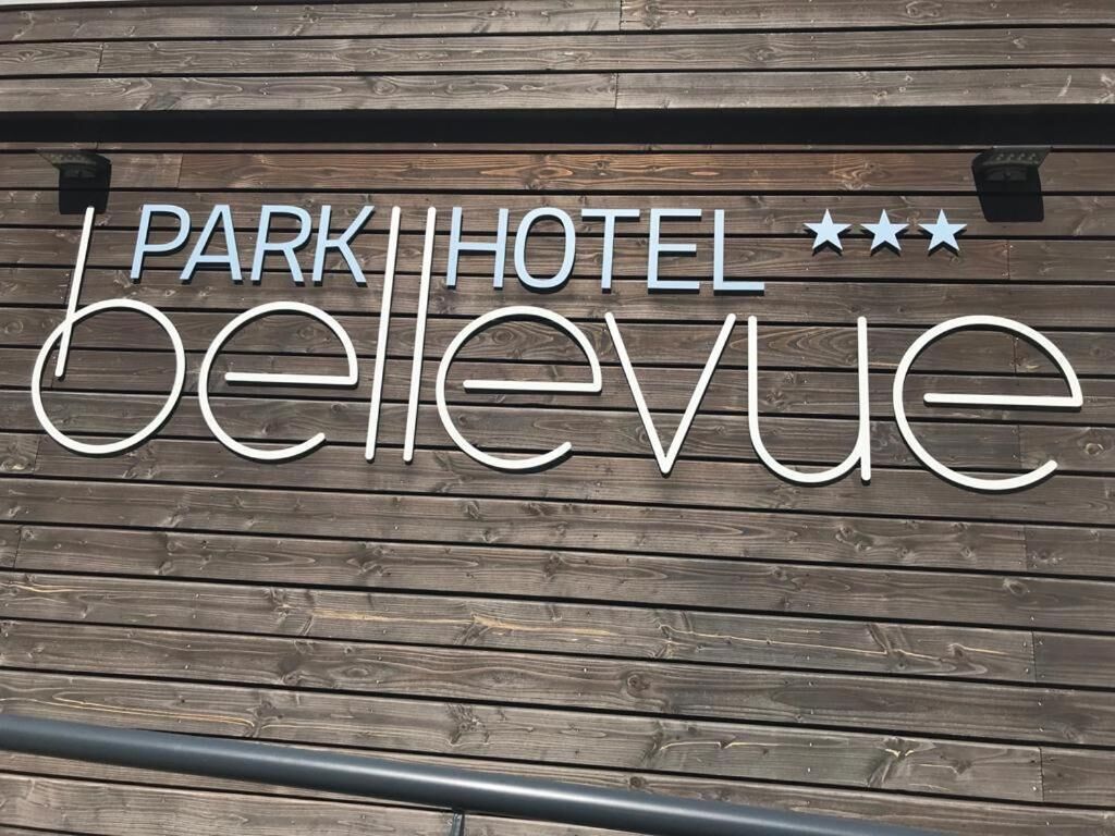En trævæg med teksten "PARK HOTEL bellevue" og tre stjerner over den.