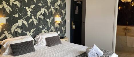 A hotel room with a large bed, two bedside tables, a dark door, and a bathroom visible through an open door.