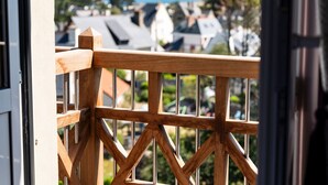A wooden balcony railing with a view of houses and the sea in the background. - L'Escale Hôtel Bellevue (Tregastel)