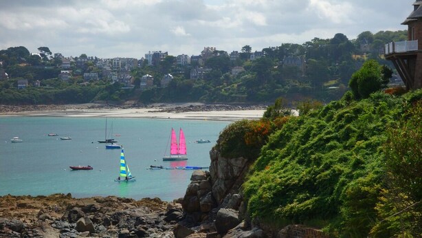 A coastal scene with a rocky shoreline, a sandy beach, and sailboats on the water. - L'Escale Hôtel Bellevue (Tregastel)
