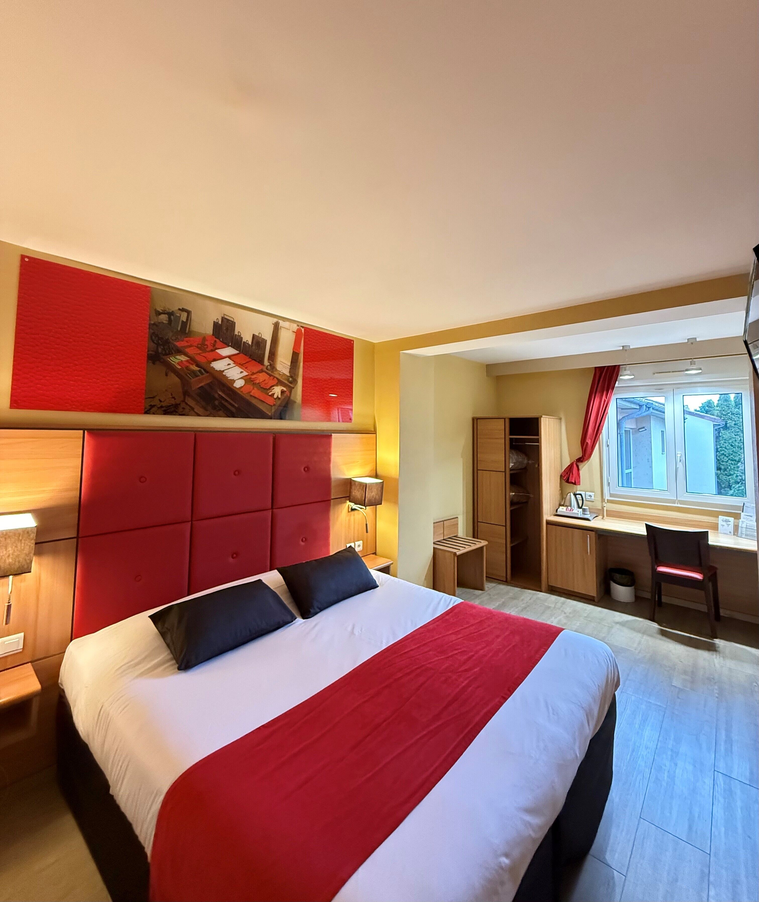 A hotel room with a large bed, a desk, and a chair.