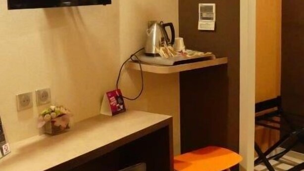 Ein kleiner, moderner Raum mit Schreibtisch, Stuhl und einem an der Wand befestigten Fernseher.