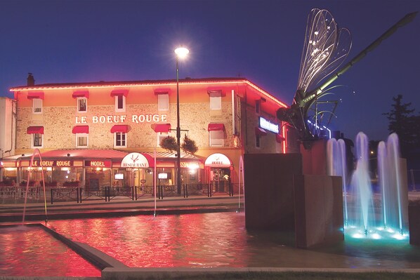 A hotel with a red facade, multiple dining areas, and a fountain. - The Originals City, Hôtel Le Boeuf Rouge, Saint-Junien (Saint-Junien)
