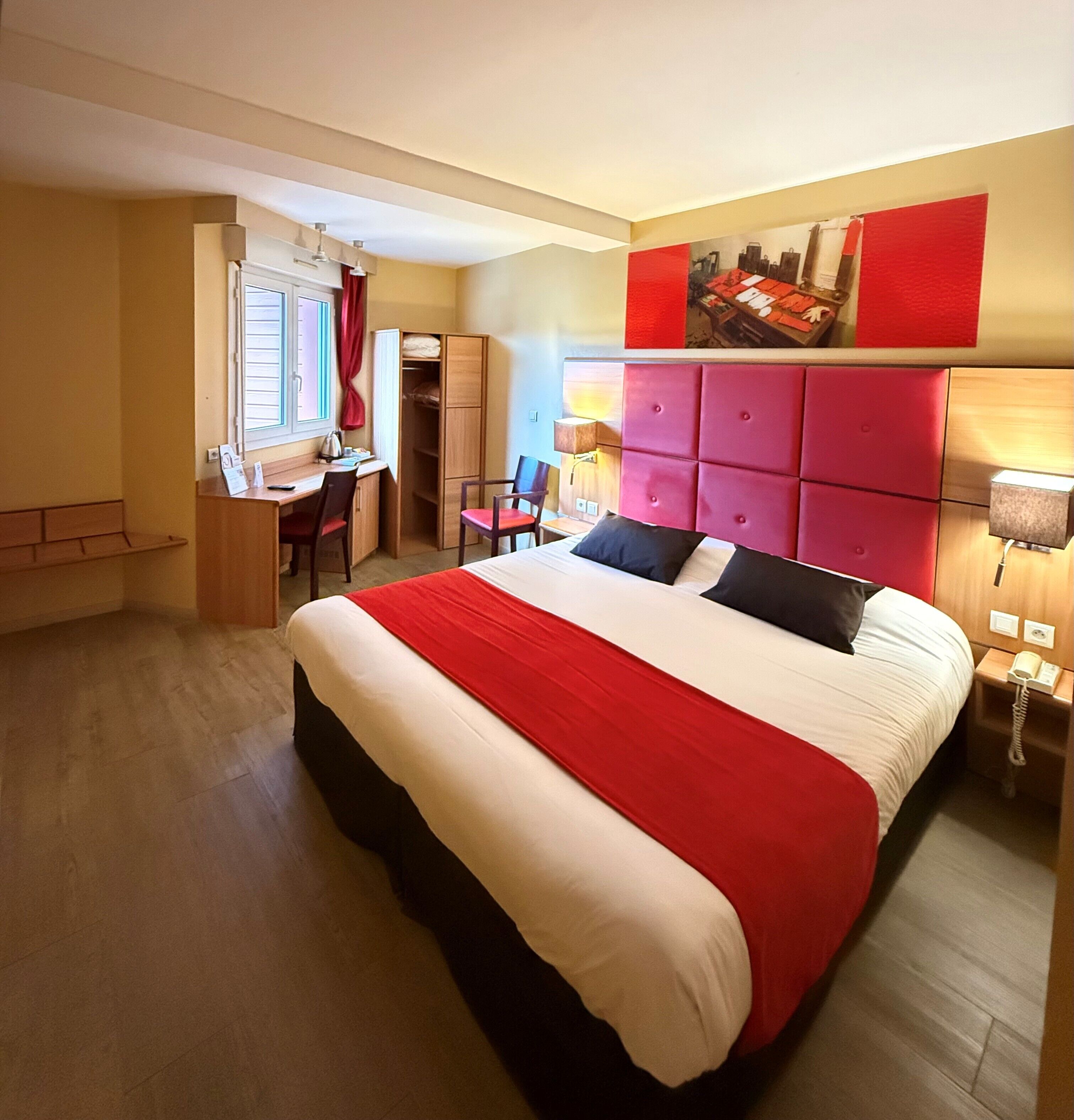 Ein Hotelzimmer mit einem großen Bett, einem Schreibtisch, einem Stuhl und einem Kleiderschrank.