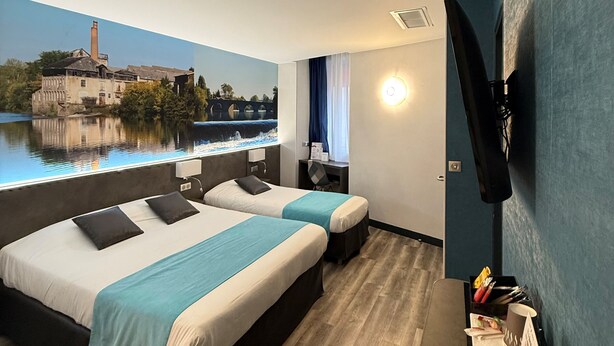 A hotel room with two beds, a TV mounted on the wall, a window with a view of a building and water, and a remote control on the floor. - The Originals City, Hôtel Le Boeuf Rouge, Saint-Junien (Saint-Junien)