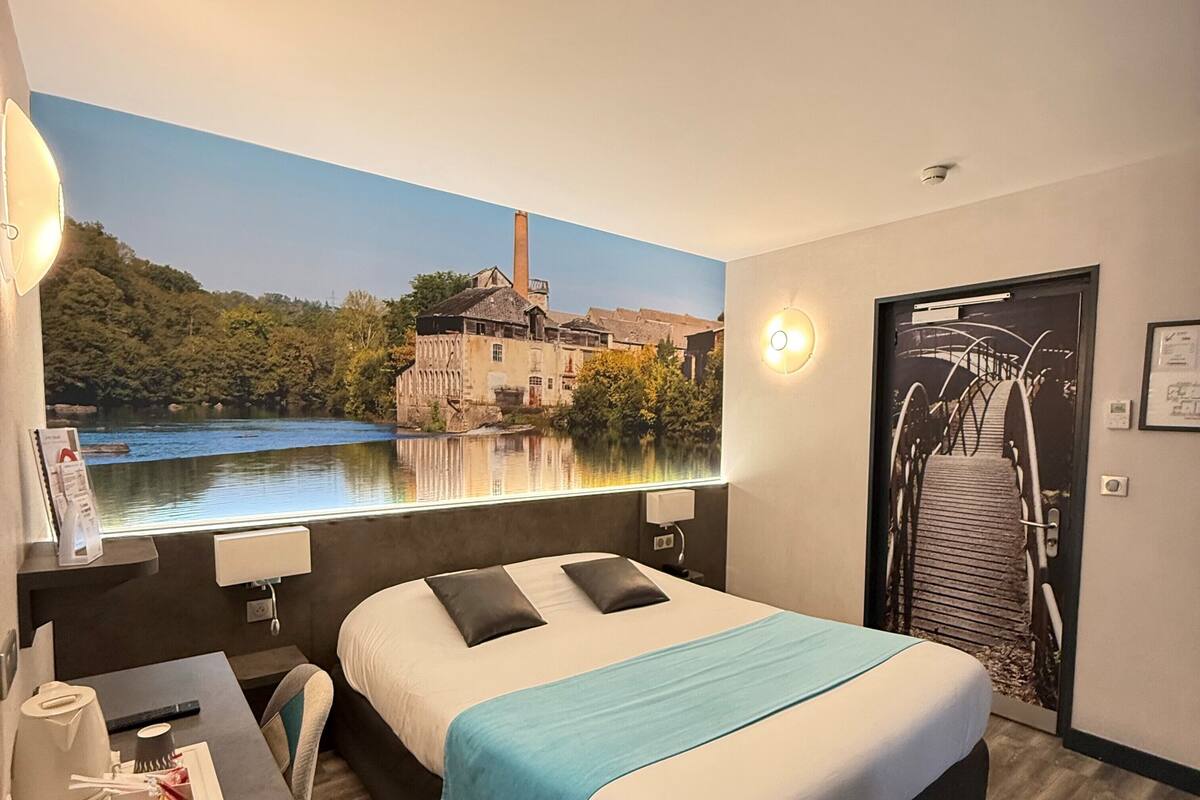 Una habitación de hotel con una cama grande, un escritorio con lámpara y un mural de un paisaje pintoresco.