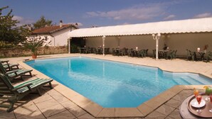 A swimming pool with lounge chairs and a covered patio area. - The Originals City, Hôtel Le Boeuf Rouge, Saint-Junien (Saint-Junien)