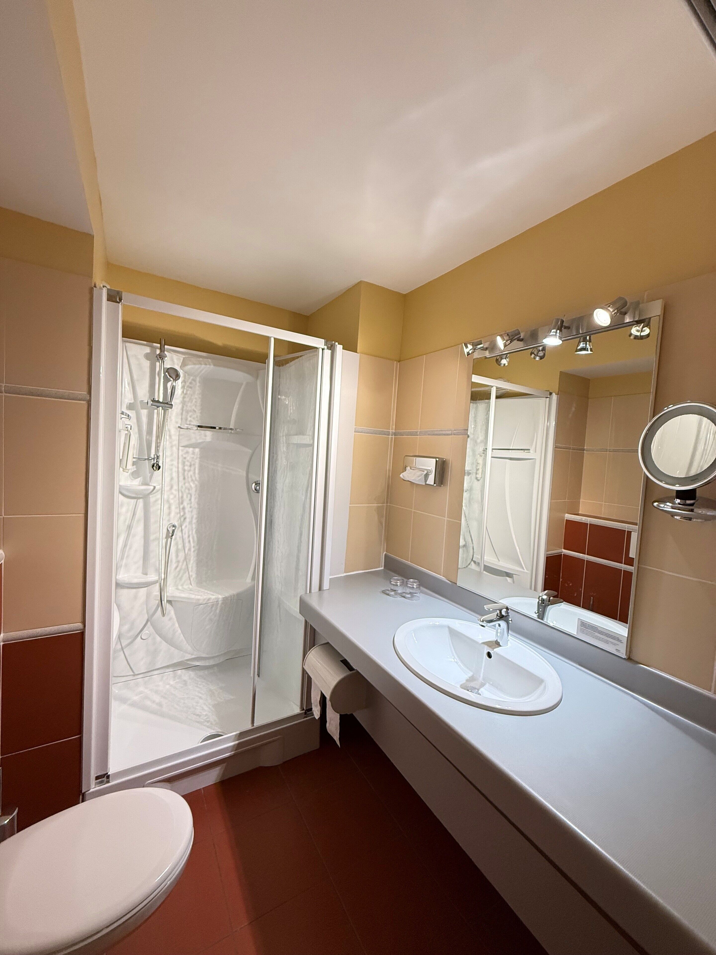 A bathroom with a shower, toilet, sink, and mirror.