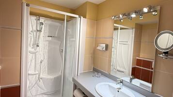 A bathroom with a shower, toilet, sink, and mirror.