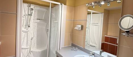 Un baño con ducha, inodoro, lavabo y espejo.