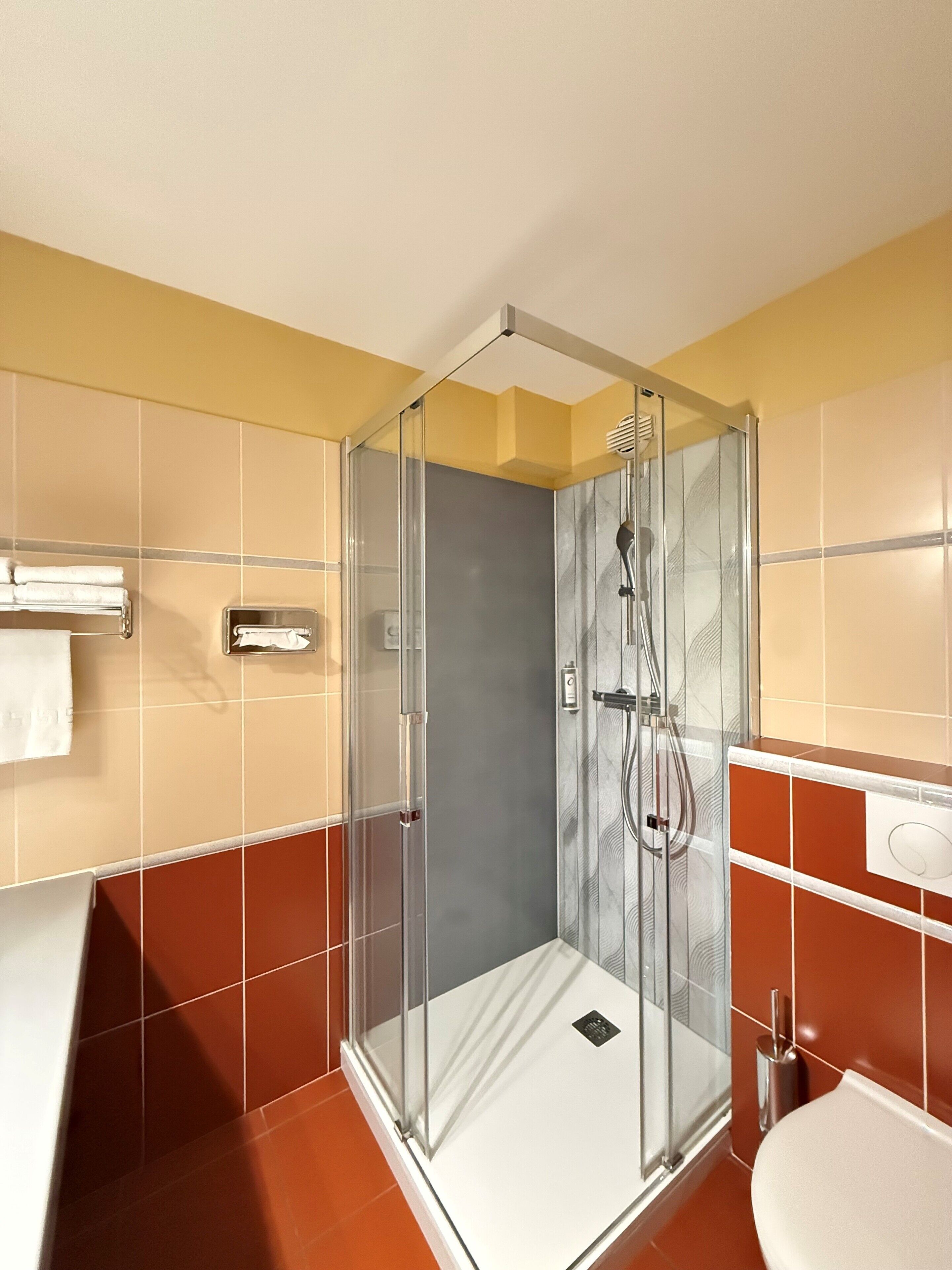 A modern bathroom with a glass-enclosed shower, a white sink, and a towel rack.