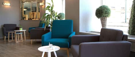 Een moderne loungehoek met zitplaatsen, een tafeltje en potplanten.