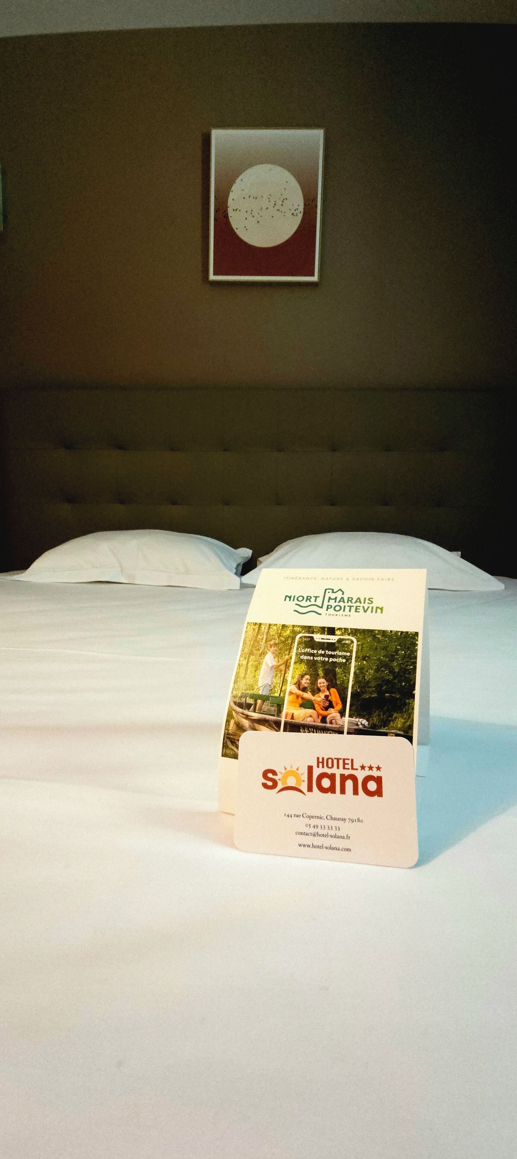 A neatly made bed with a brochure for Hotel Solana on it.