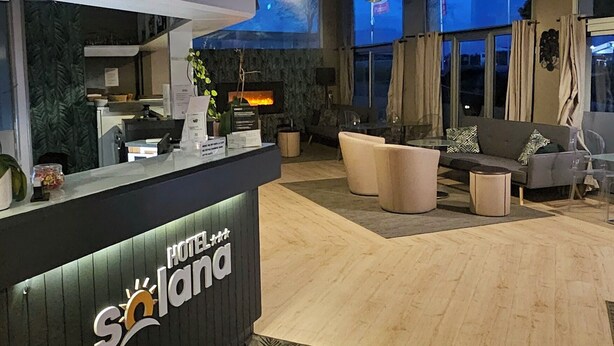 Un'area di reception di un hotel dal design moderno, con scrivania, zona salotto e un'ampia finestra.