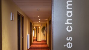 Un corridoio d'albergo con tappeto rosso e un cartello sulla parete destra che indica 'Accès chambres'.