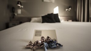 Una camera d'albergo con un letto rifatto, una lampada da comodino e un biglietto sul letto.