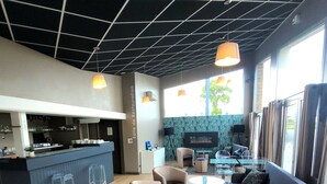 Un'area lounge moderna con un bar, posti a sedere e una televisione.