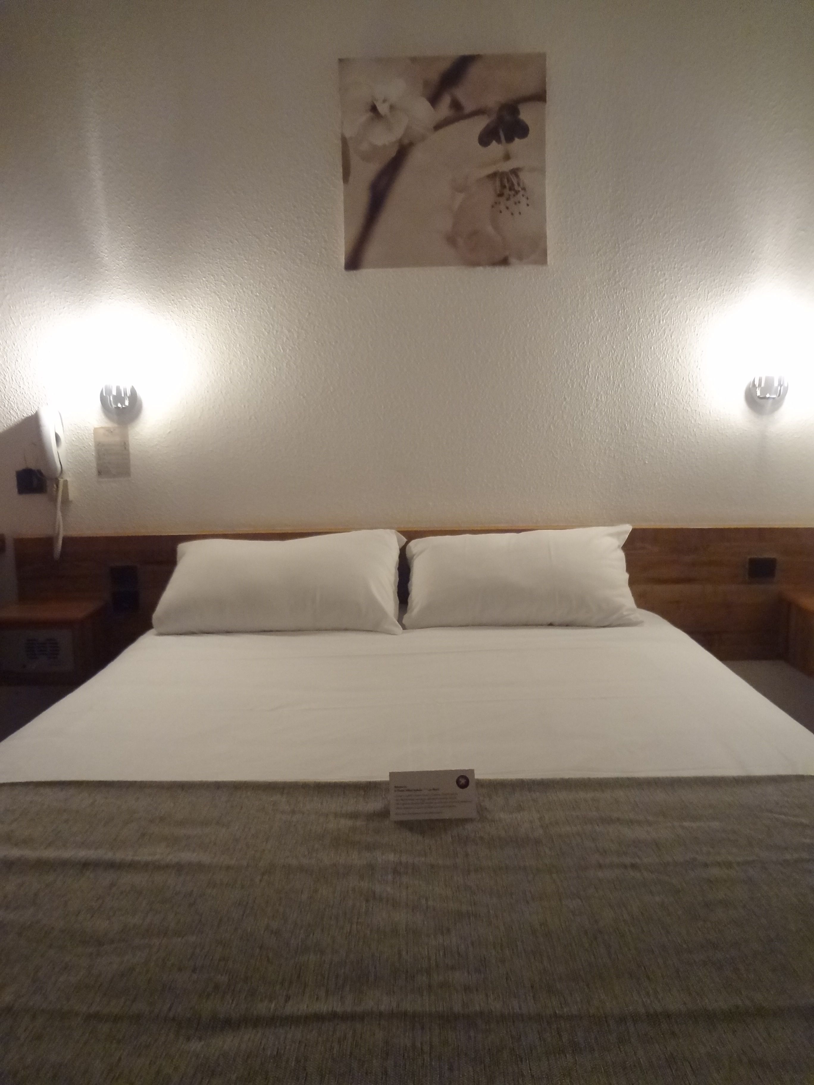Una habitación de hotel con una cama grande, dos mesitas de noche y una obra de arte colgada en la pared.