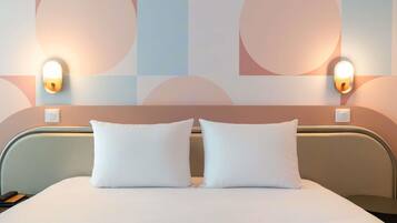 Una habitación de hotel con una cama, dos lámparas de noche y una pared con diseños geométricos abstractos.