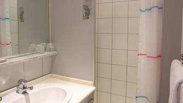 Ein Badezimmer mit Waschbecken, Spiegel, Duschvorhang und Handtuchhalter.