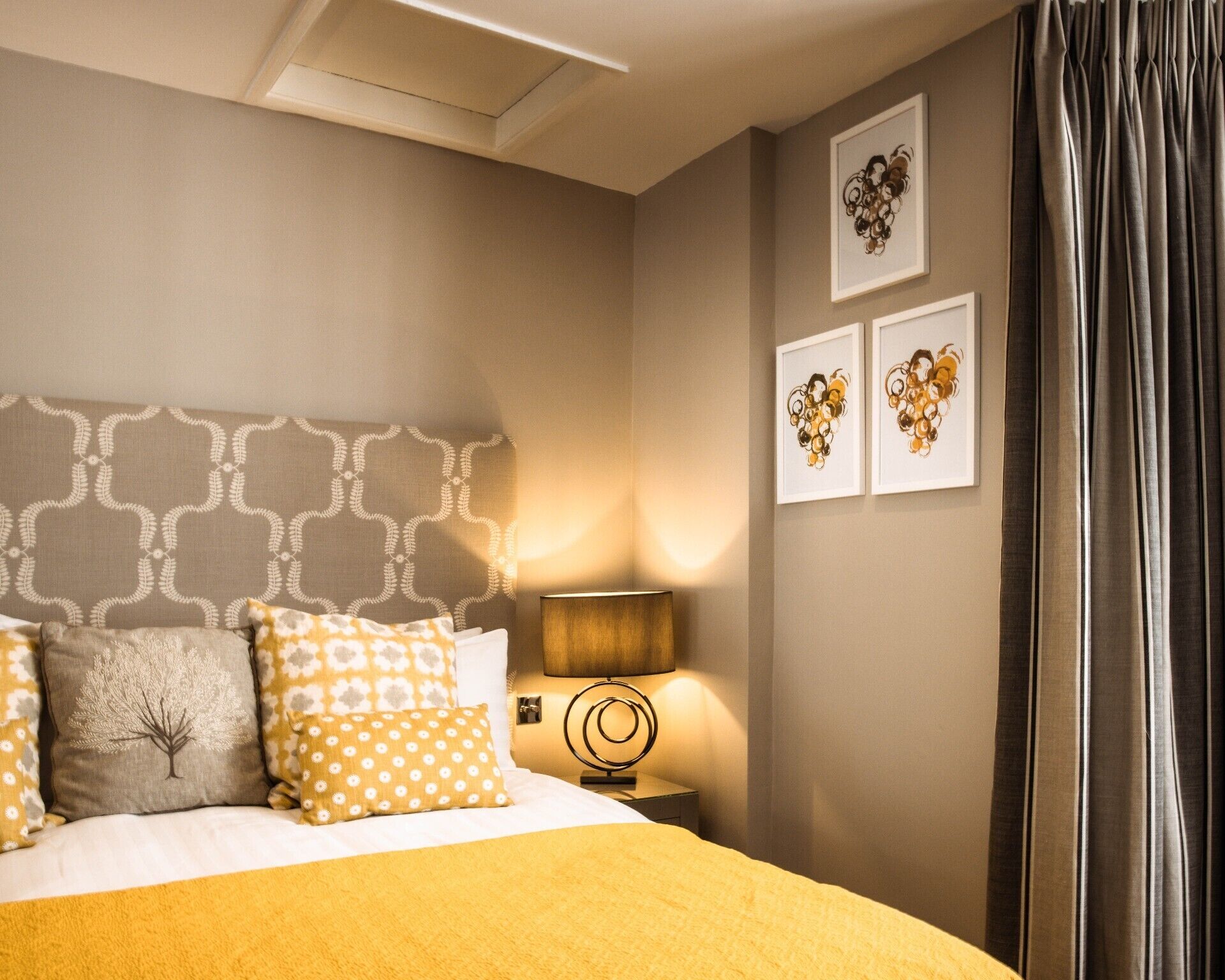 A bedroom with a bed, a nightstand, a lamp, and wall art.