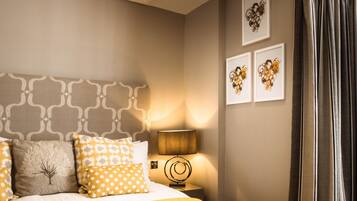 A bedroom with a bed, a nightstand, a lamp, and wall art.