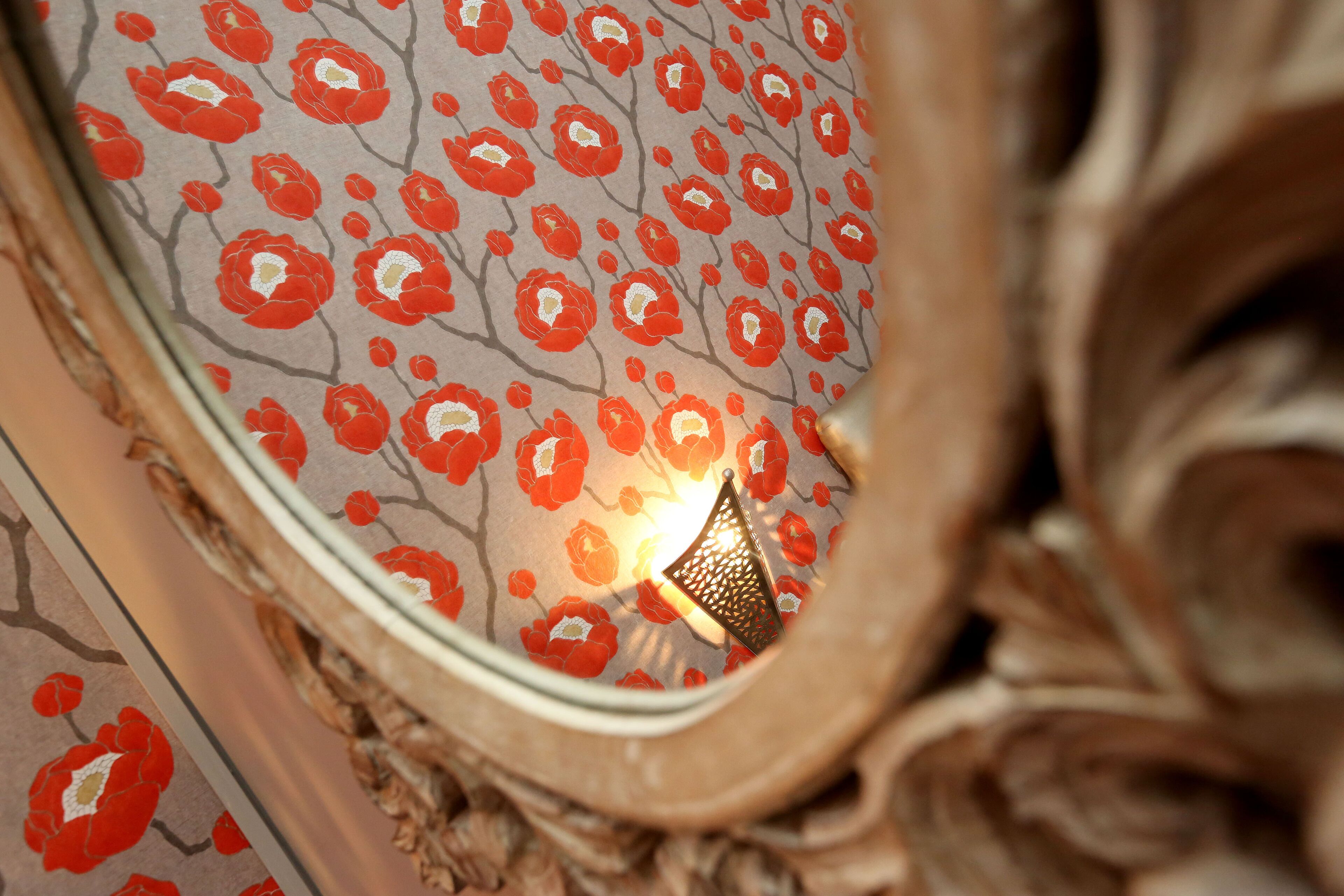 A close-up of a wall with a floral pattern and a decorative metal piece.