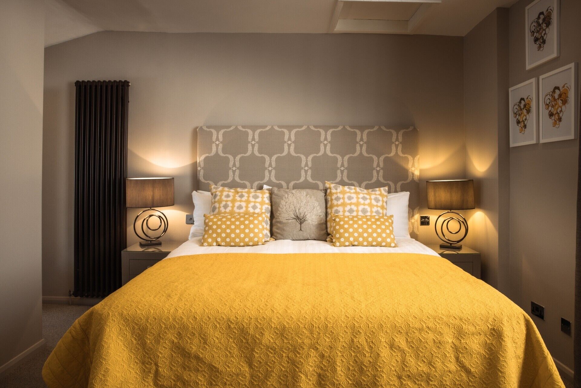 A hotel room with a large bed, two bedside tables, and a headboard with a geometric pattern.
