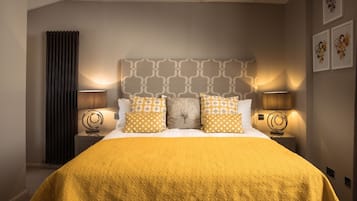 A hotel room with a large bed, two bedside tables, and a headboard with a geometric pattern.